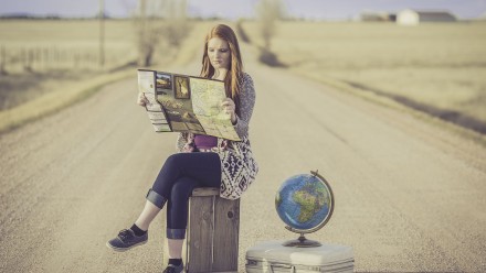 Girl reading a map with a globe next to her