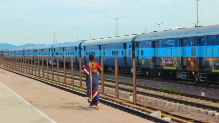 A solitary Indian lady walks beside a train