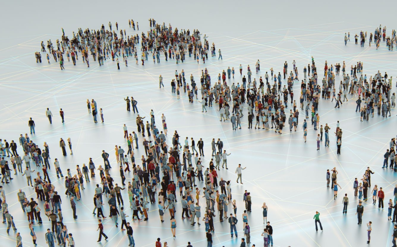 A large group of diverse people gather on a grid-patterned, illuminated floor.