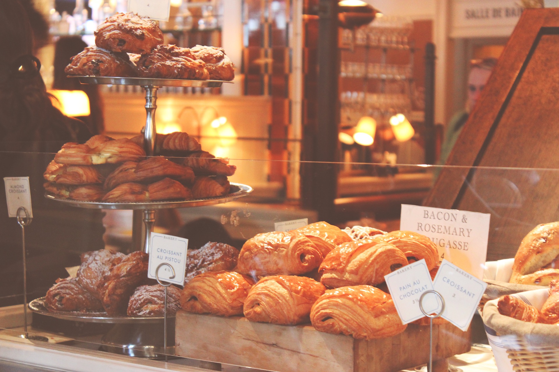 A display of various croissants and pastries in a warmly lit bakery.