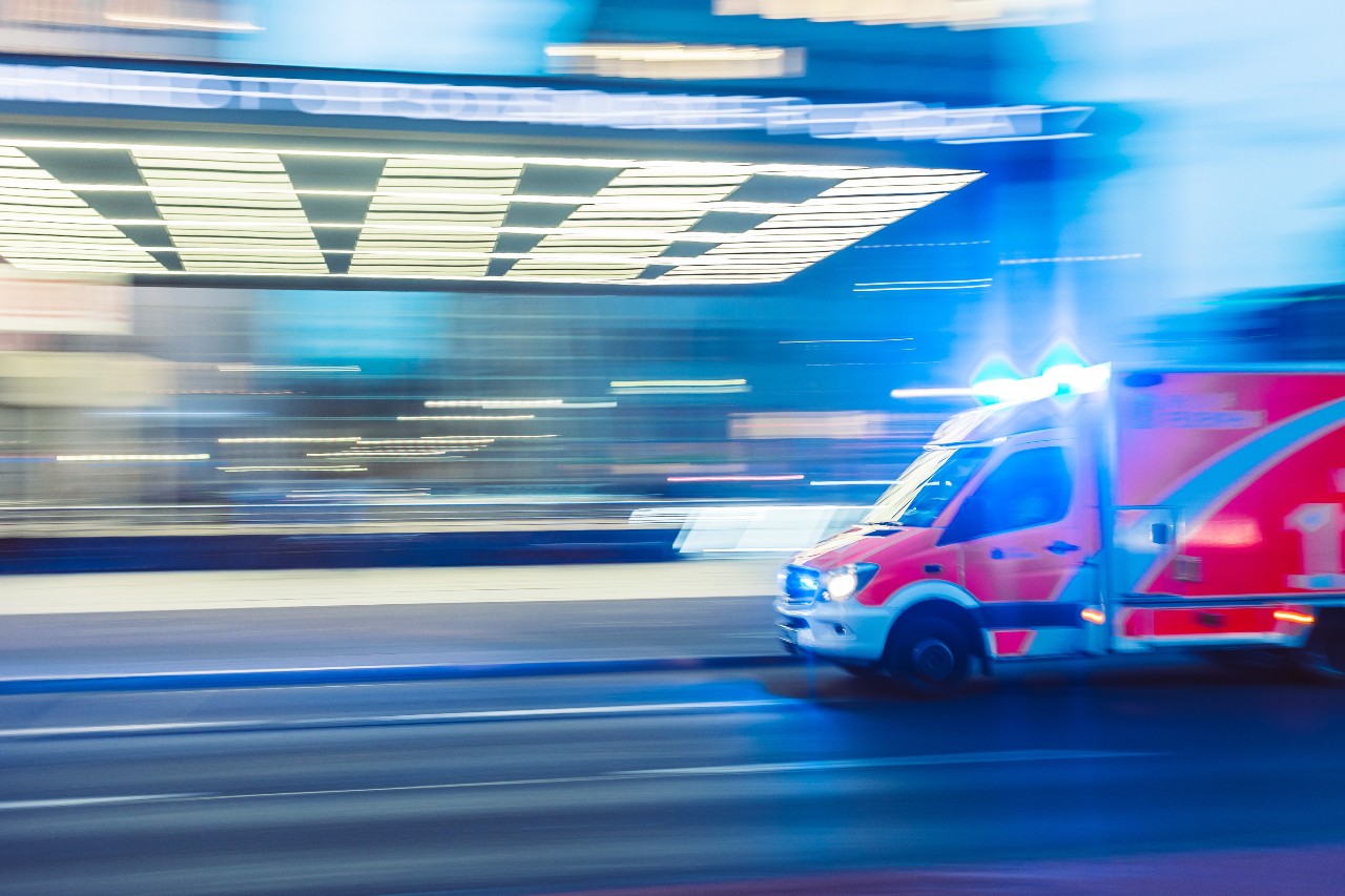 A motion-blurred image of an ambulance speeding at night with lights flashing.