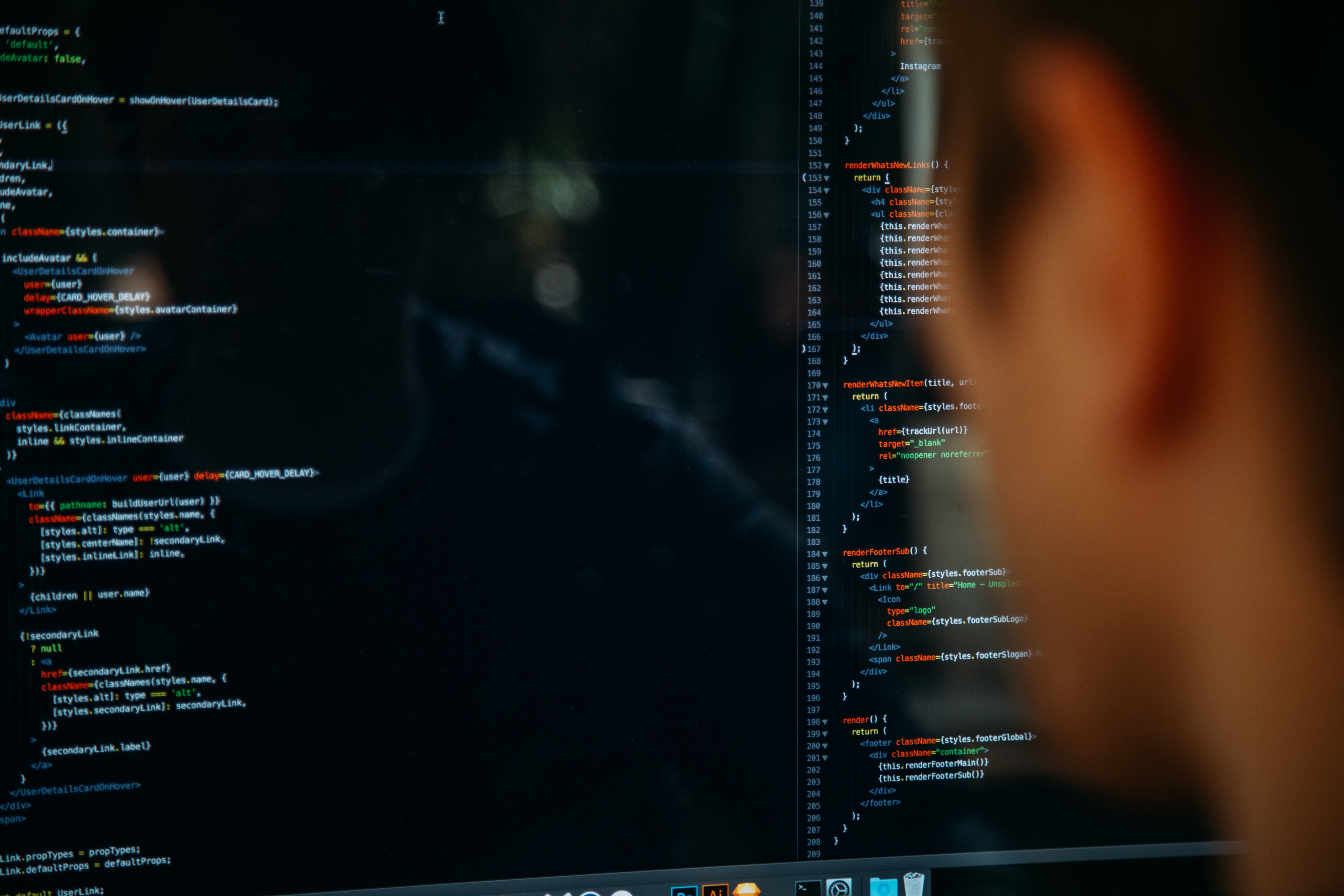 Person coding, reflected faintly on a computer screen displaying code.