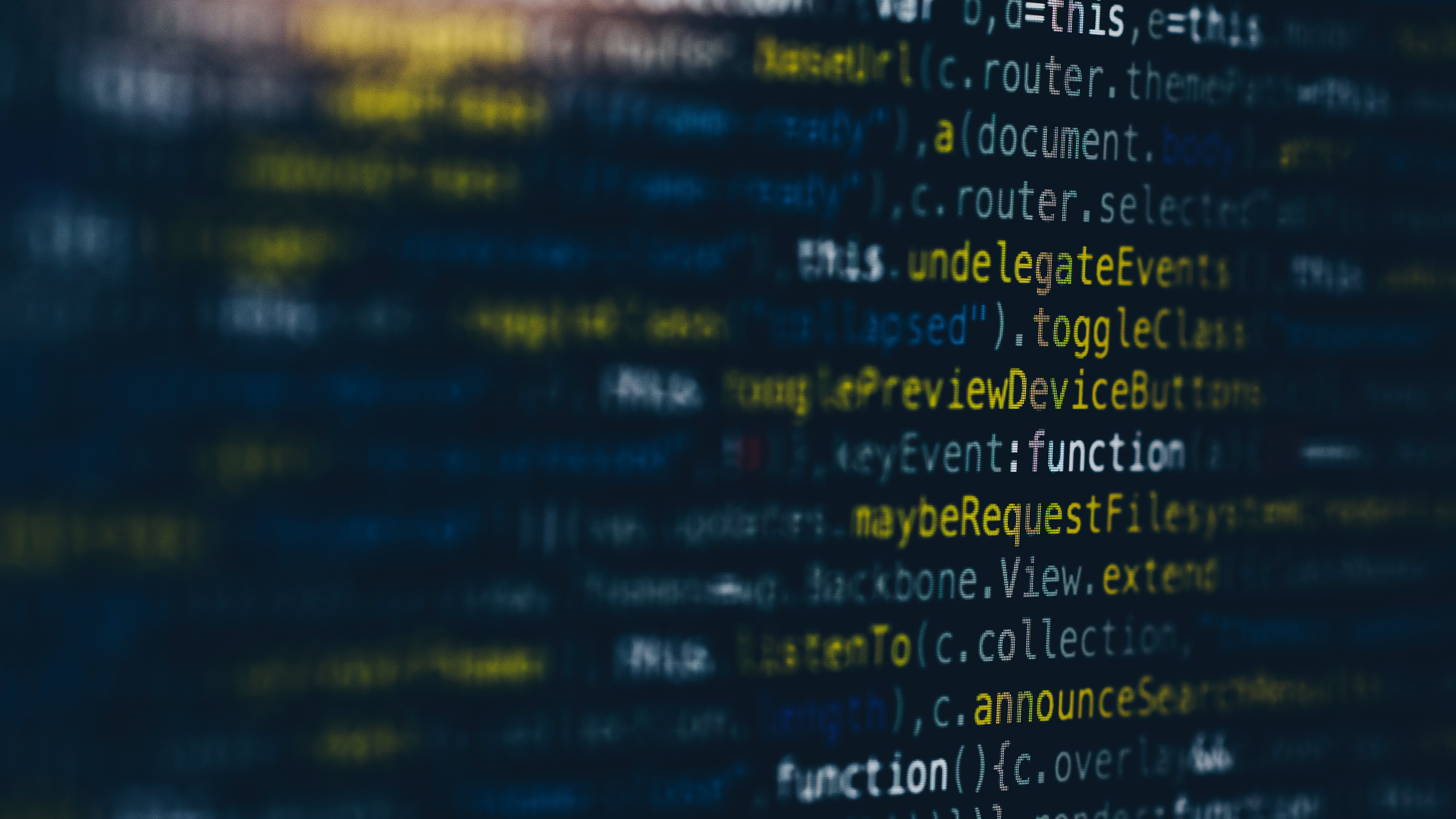 Blurry image of computer code with highlighted text in blue and yellow on a screen.