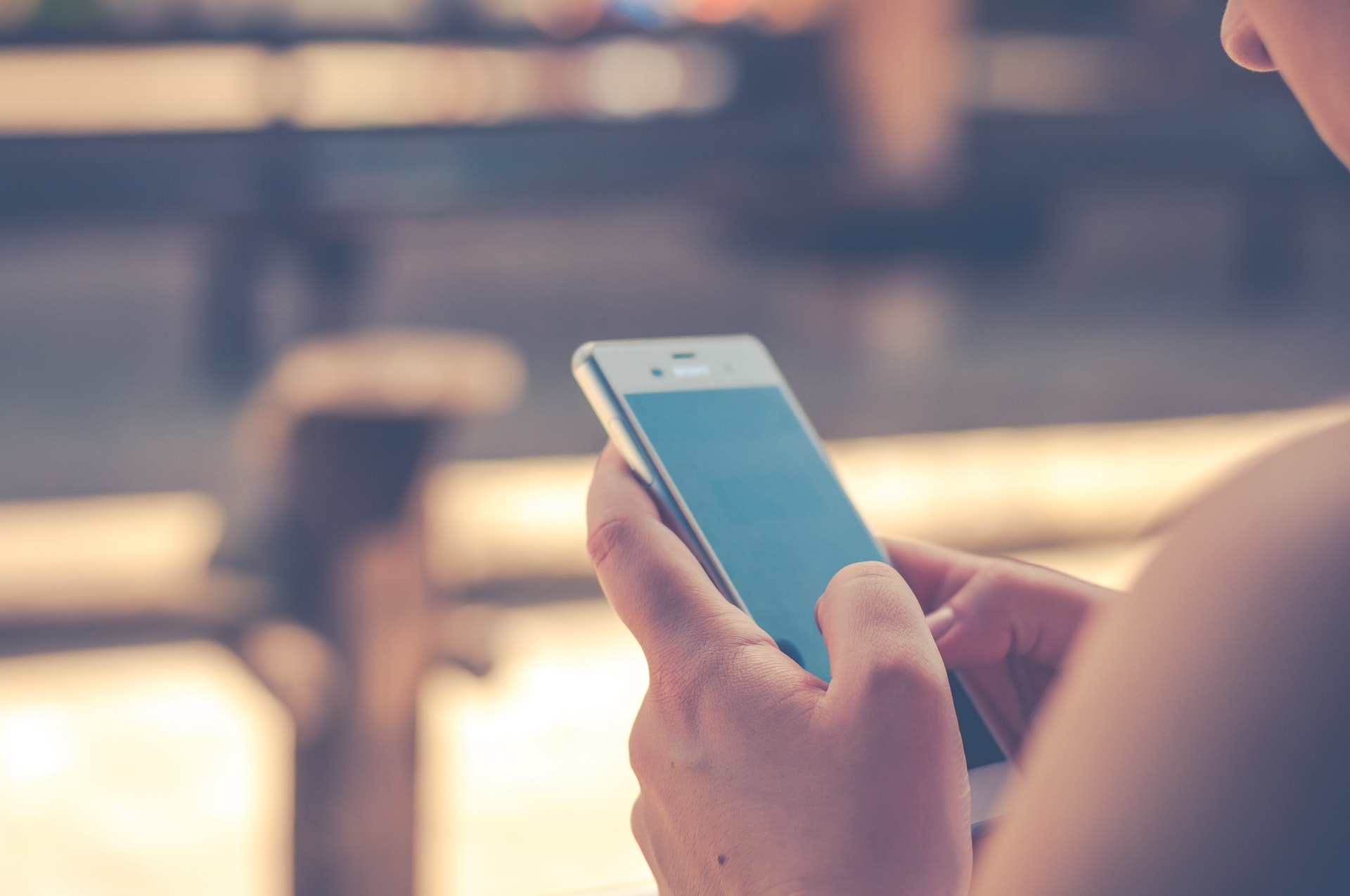 A person using a smartphone, focusing on the screen with both hands.