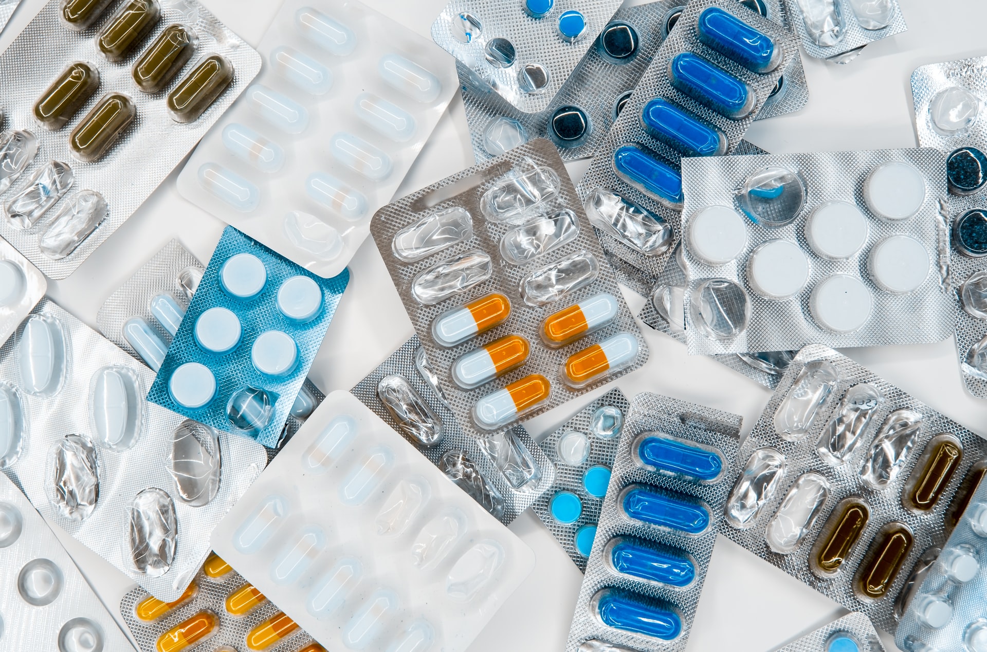 Assorted medications in various colored capsules and tablets, some packaged in blister packs.