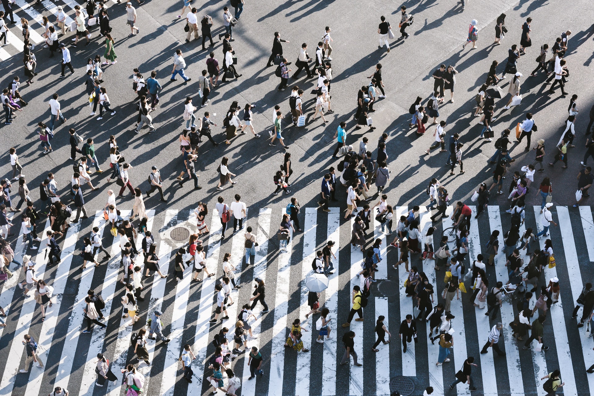 Aerial view of a bustling pedestrian crossing with many people walking in various directions on white zebra crossings.