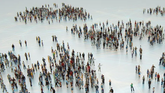 A large group of diverse people gather on a grid-patterned, illuminated floor.