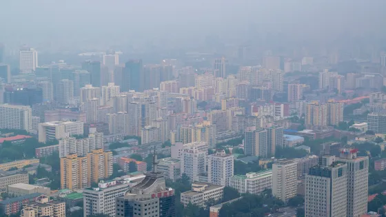 Aerial view of a dense urban area with numerous high-rise buildings under a hazy sky.
