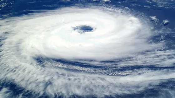 Satellite view of a powerful hurricane with a well-defined eye, surrounded by swirling clouds over the ocean.