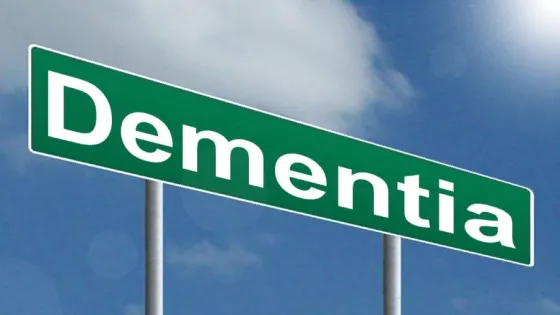 A green road sign with the word "Dementia" against a blue sky background.