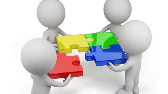 Four 3D figures collaborate to fit together large, colorful puzzle pieces.