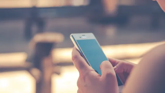 A person using a smartphone, focusing on the screen with both hands.
