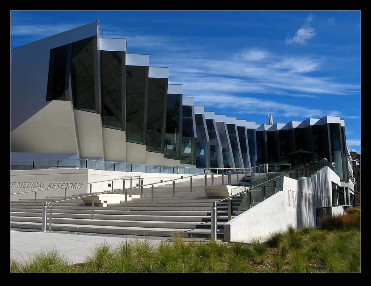 Modern architectural building of a medical research institute with reflective glass and geometric white panels under a blue sky.