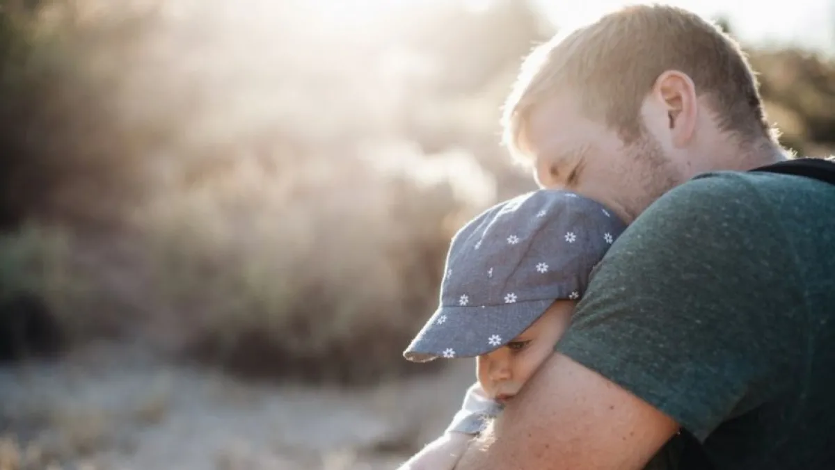 Dad hugging baby. Conversation on parental leave.