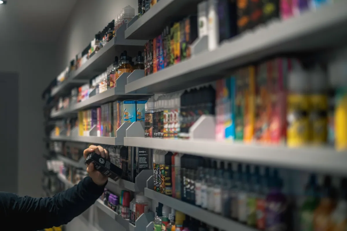 A person's hand reaching out for a product on a shelf filled with various packaged goods in a store.
