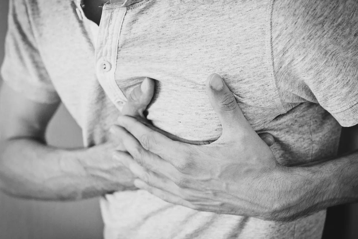 A person clutching their chest in discomfort, depicted in black and white.