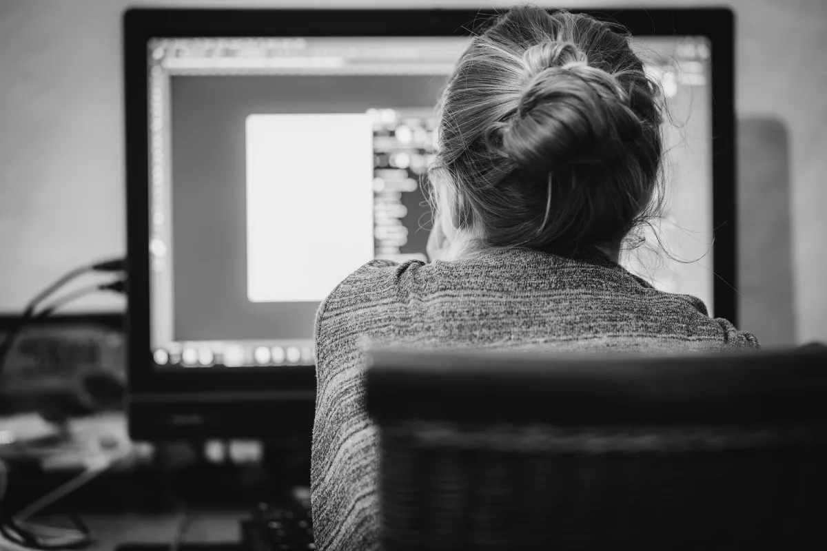 Woman with a bun hairstyle working on a computer in an office setting.