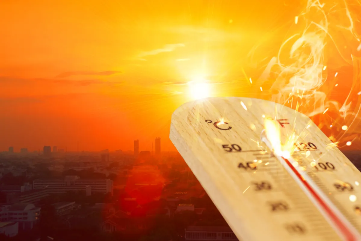 A thermometer reading high temperatures overlaid on a city skyline bathed in a fiery orange sunset.