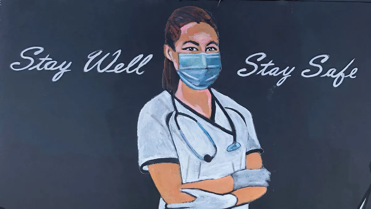A mural of a nurse wearing a face mask with the words "Stay Well Stay Safe" written above and beside her.