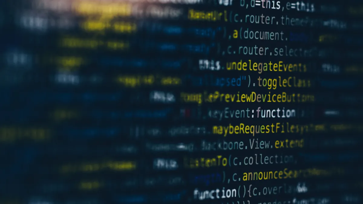 Blurry image of computer code with highlighted text in blue and yellow on a screen.