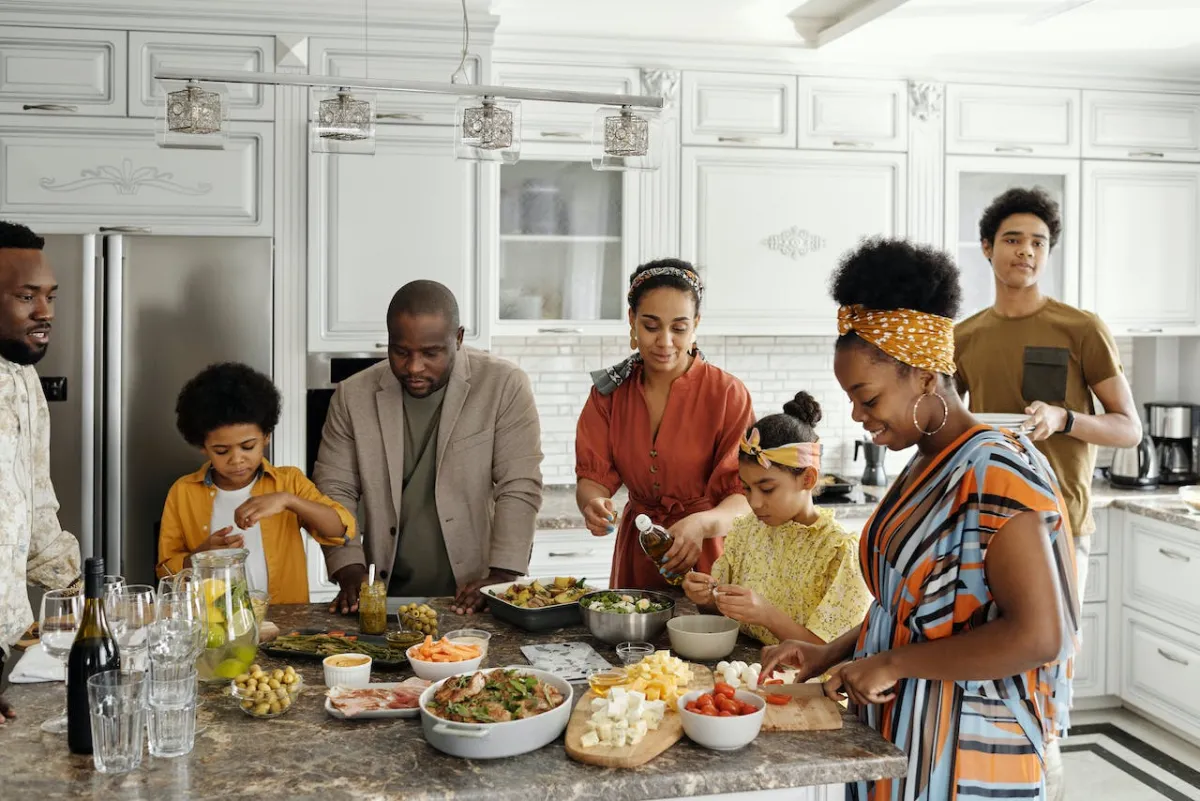 A diverse family prepares a meal together in a well-equipped kitchen.
