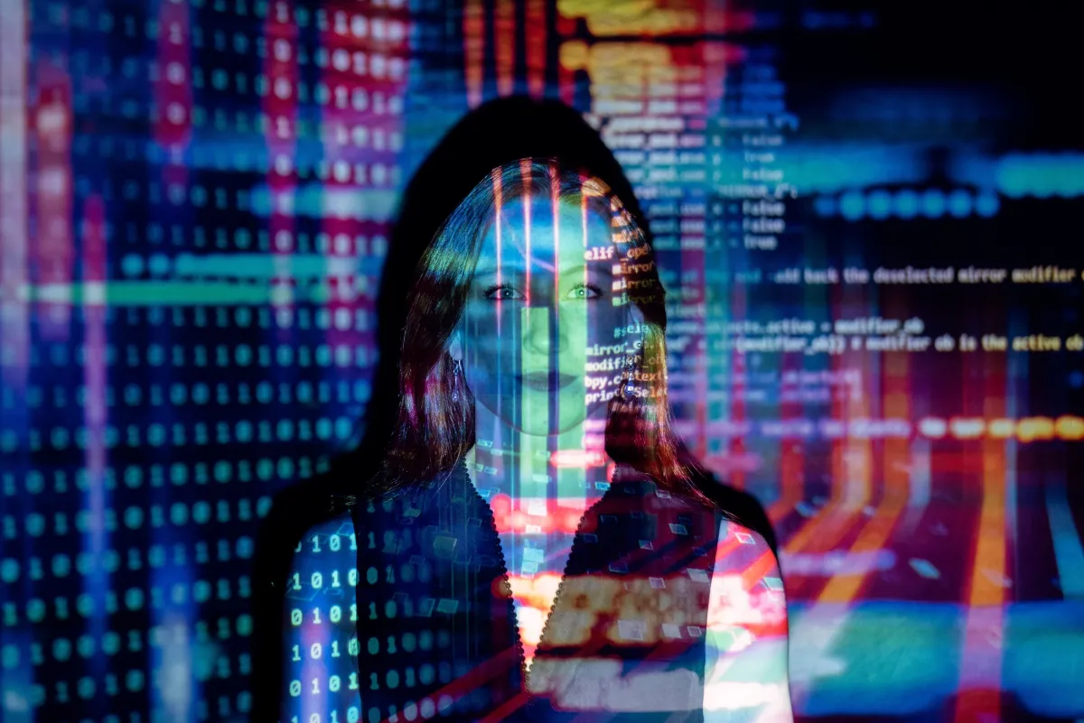 A woman's face overlaid with colorful digital data and code, creating a futuristic visual effect.