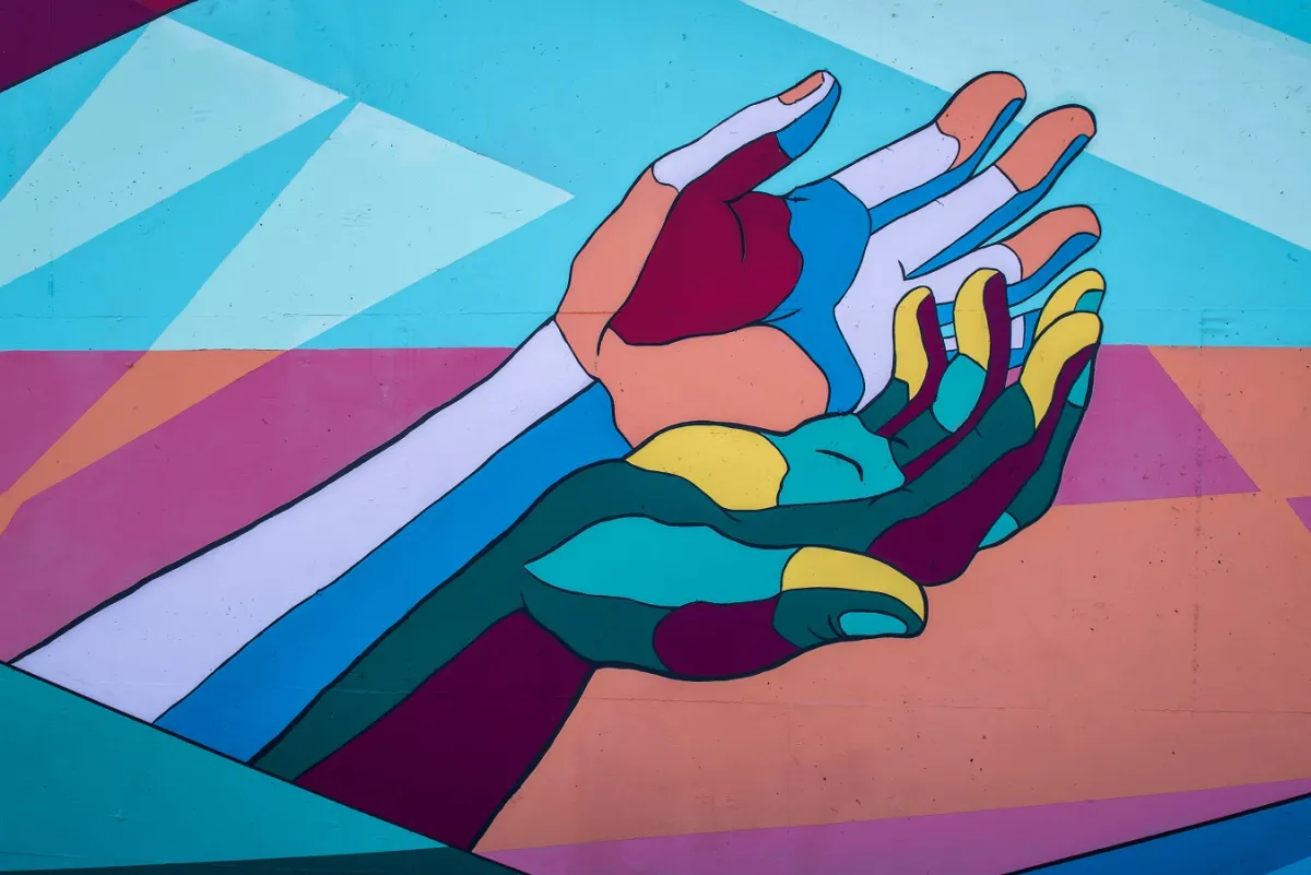Colorful mural of two intertwined hands, painted in bold geometric blocks of color.