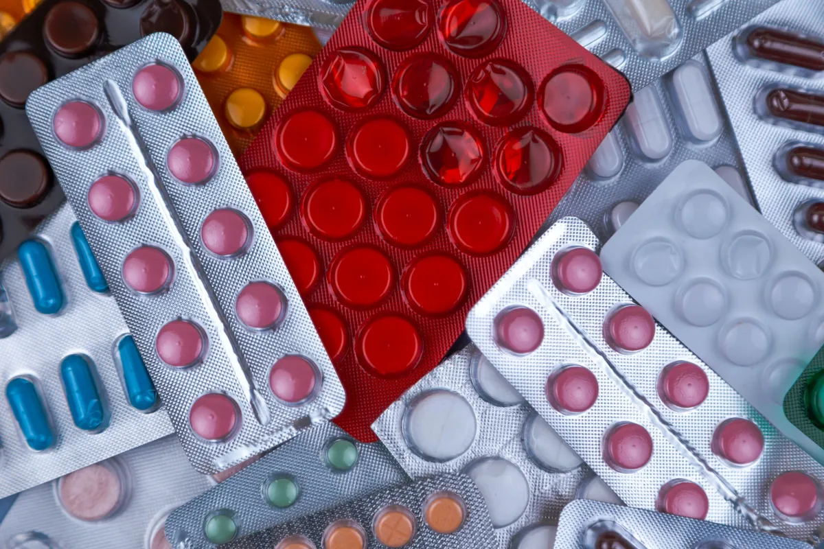 Various types of medication in different colored blister packs, including capsules, tablets, and gel caps.