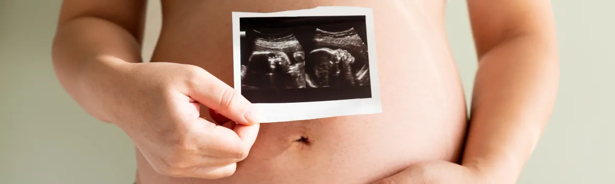Woman holding her large pregnant belly and ultrasound imagery