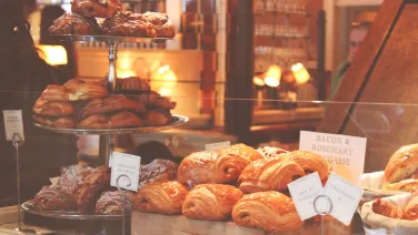 A display of various croissants and pastries in a warmly lit bakery.